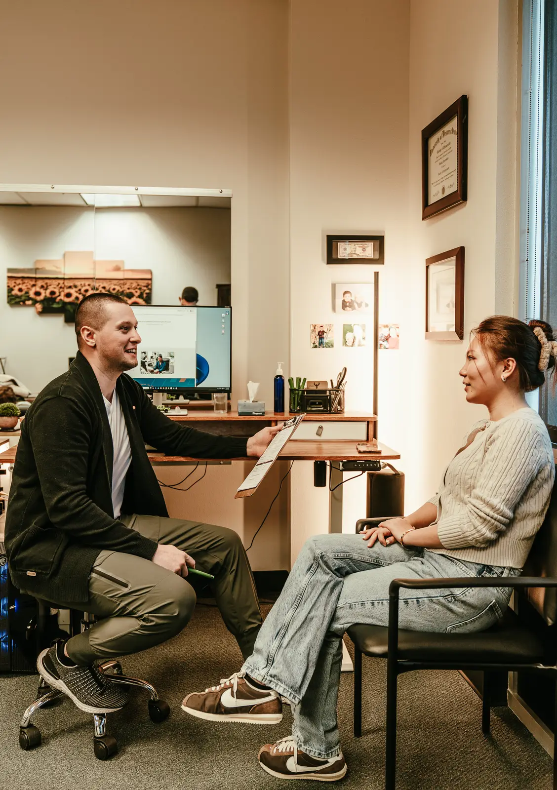 Dr. Nikolay Chernukhin, D.C., consulting with a patient (University of Western States diploma visible)